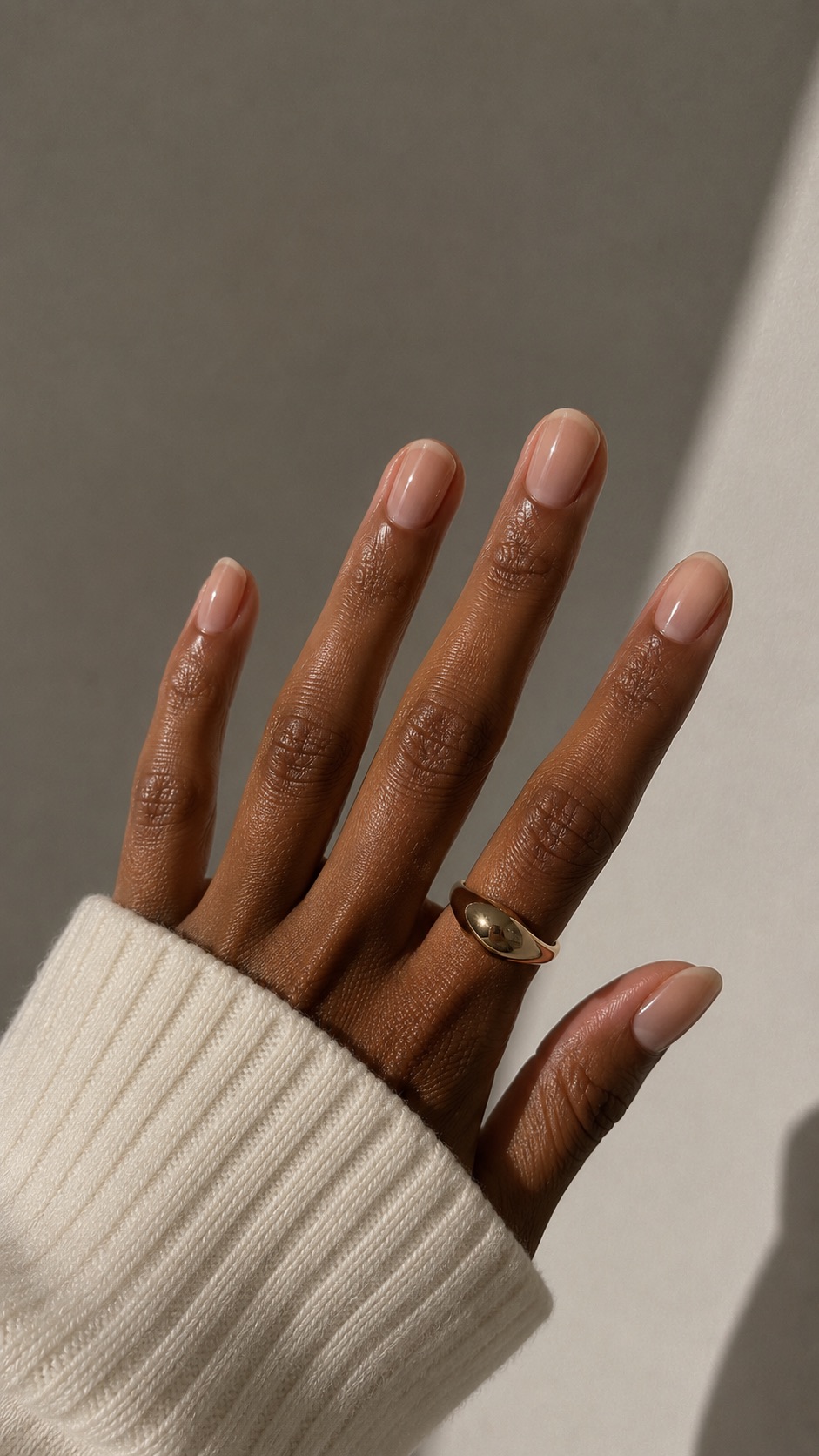 Natural glossy manicure on a hand with a gold ring