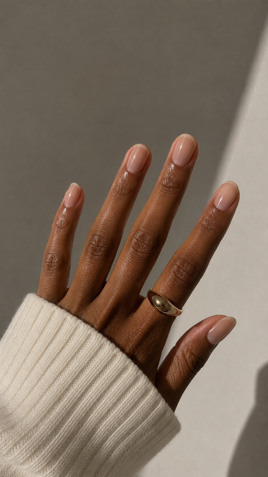 Natural glossy manicure on a hand with a gold ring