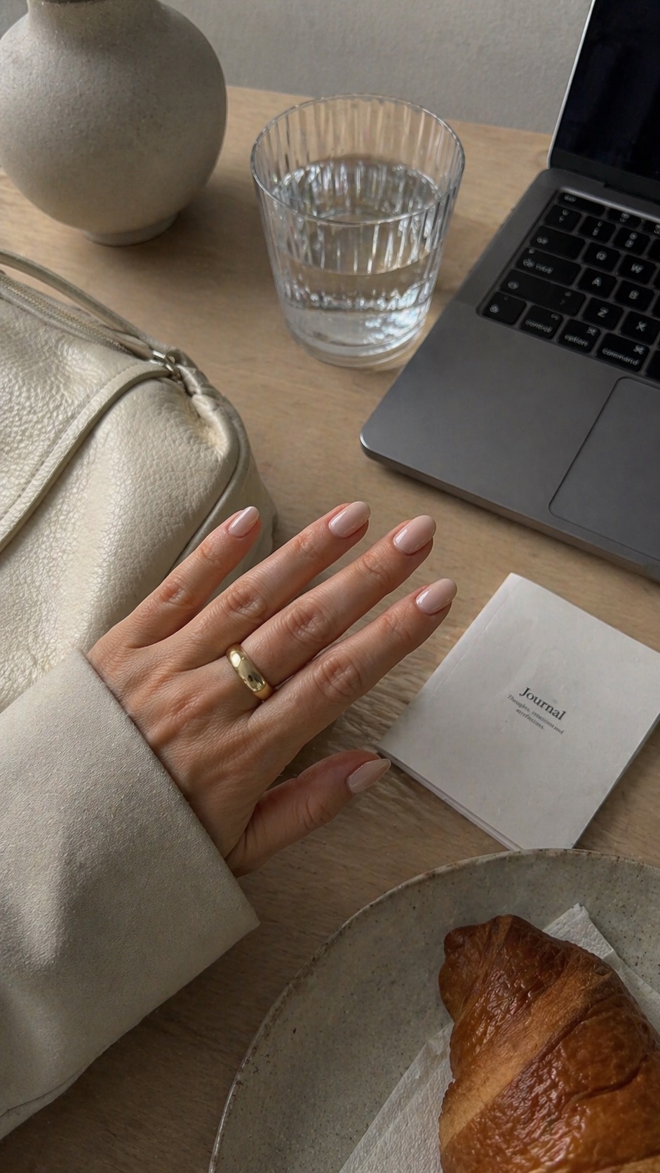 Minimal manicure at a table with a glass of water and notebook
