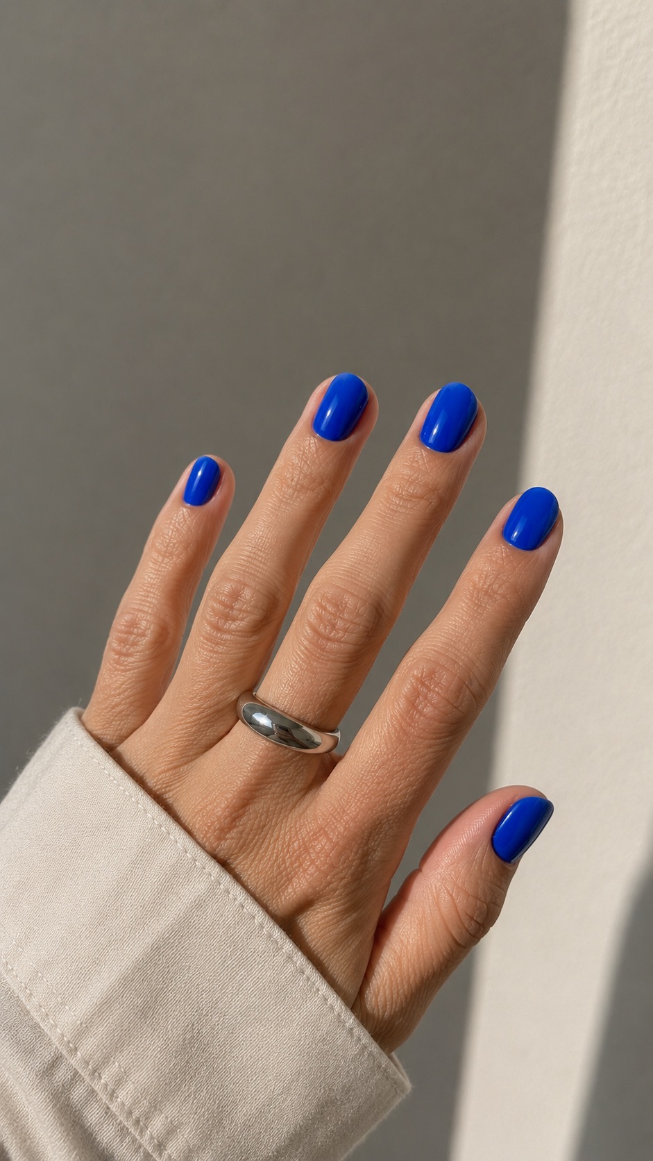Blue minimalist manicure on a hand with a silver ring
